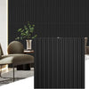 A dark vertical slat wall panel in a modern interior setting with a chair and potted plant.