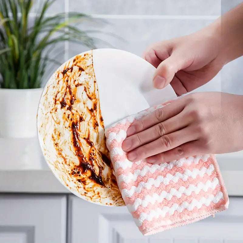 Eine Hand wischt ein rundes, weißes Reinigungstuch mit einem rosa Korallen-Fleece-Tuch.