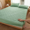 A teal quilted mattress protector with extra padding is shown on a wooden bed frame.