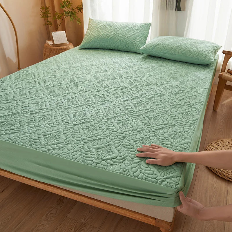 A teal quilted mattress protector with extra padding is shown on a wooden bed frame.