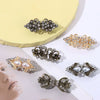 A collection of vintage-style floral and ornate metal clips used to fasten cardigans and shawls.