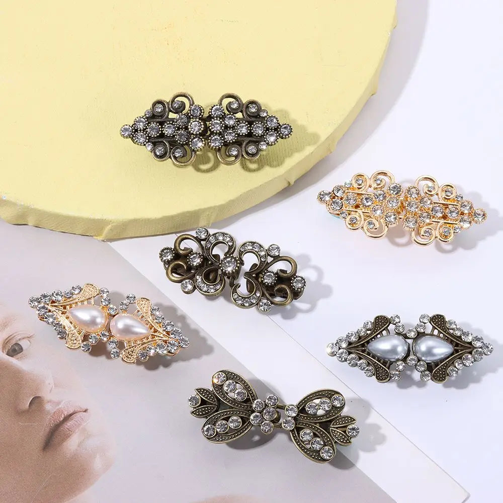 A collection of vintage-style floral and ornate metal clips used to fasten cardigans and shawls.