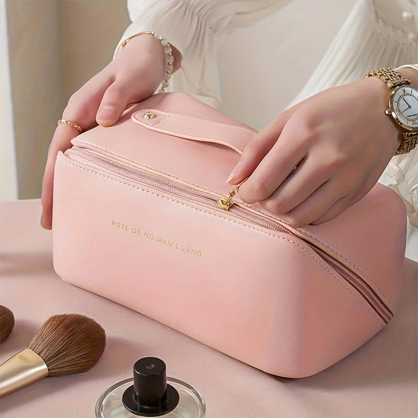 A person holds a pink travel makeup organizer bag with a zipper, resting on a light surface.