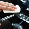 A hand wipes a black retractable car mirror or window cleaning wiper with a white cloth.