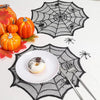 A Halloween display featuring pumpkins, a white donut, and a black spider web design on a white surface.