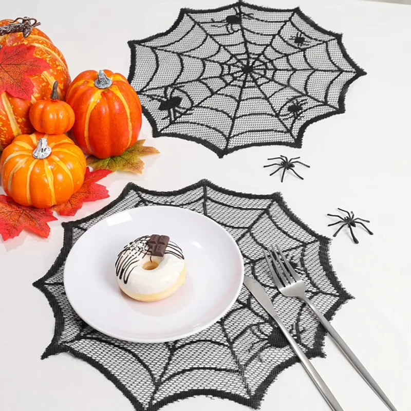 A Halloween display featuring pumpkins, a white donut, and a black spider web design on a white surface.