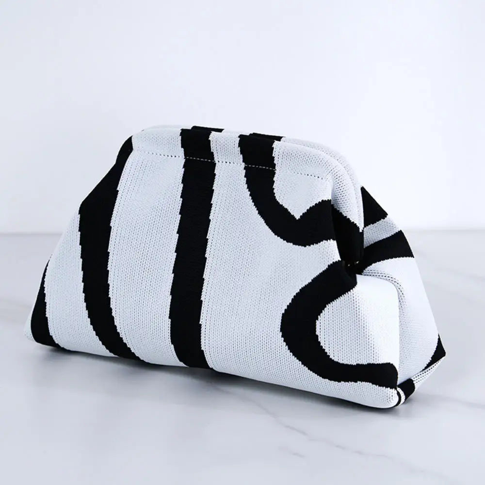 Pochette en crochet rayée blanche et noire, pliée sur une surface de marbre.