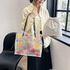 A woman holds a clear transparent tote bag with a patterned design and a separate fabric pouch.