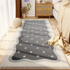 A gray and white patterned area rug placed on a wooden floor in a bright room.