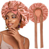A woman models a satin sleeping bonnet in a dusty rose color with an adjustable tie.