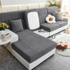 A modern gray sofa slipcover with white cushions and a light wood accent table in a bright living room setting.