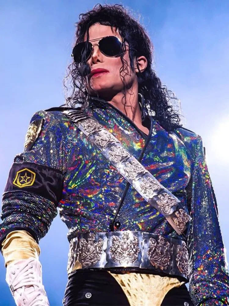 A person wearing a sparkly blue and purple sequined jacket with silver accents and dark sunglasses.