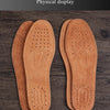 Pair of tan leather insoles displayed on a wooden surface.