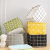 A stack of storage baskets in various patterns including green, yellow, and black plaid designs.