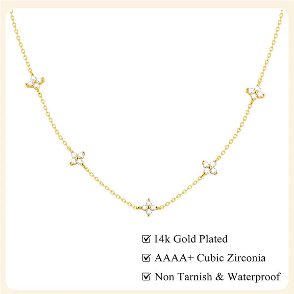 A delicate gold-plated necklace featuring small white cubic zirconia flowers and a leaf pendant.