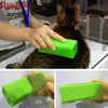 A hand is using a green silicone pet hair remover brush on a cat's fur.