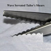 Close-up of a pair of professional stainless steel wave serrated tailor's shears resting on white fabric.