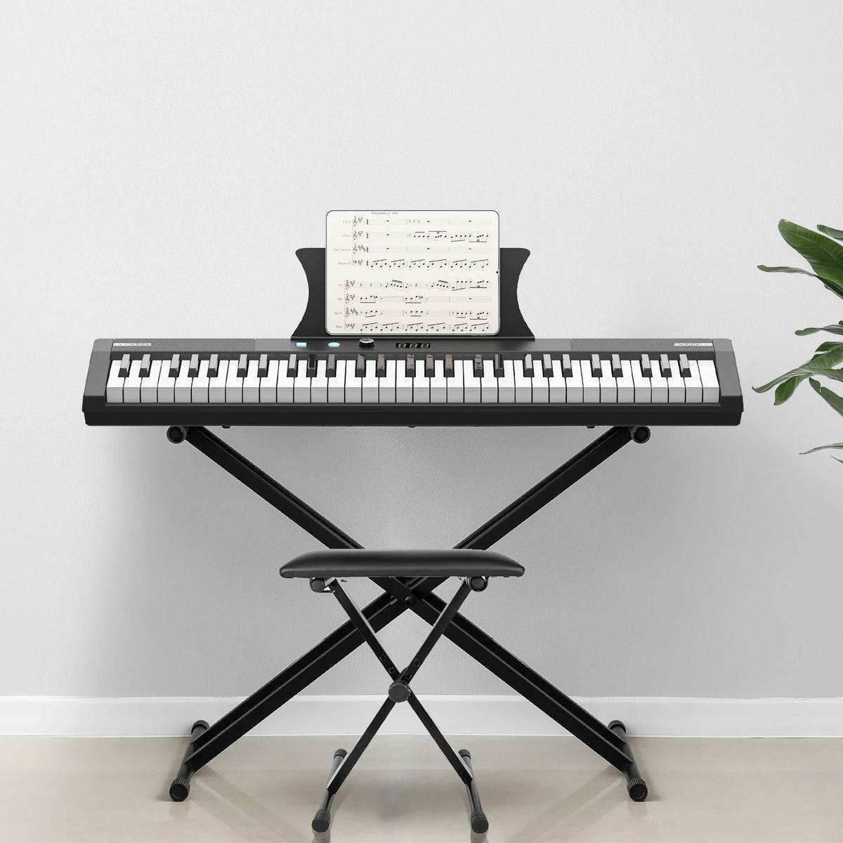 A black 61-key digital piano with a stand, bench, headphones, and pedal resting on a light gray wall.