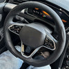A close-up view of a black steering wheel with leather covers and airbag visible inside a car