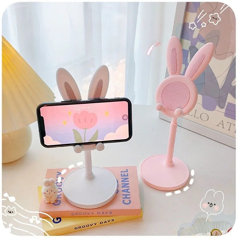 A pink rabbit mobile phone and tablet stand with a white base and pink accents on a light surface.