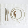 A set of six linen hemstitch napkins displayed on a white cloth with silverware and a plate.