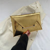 Gold crocodile pattern PU envelope clutch with a coin pocket shown against a light fabric background.