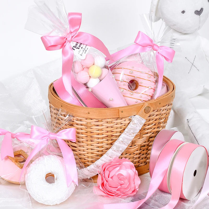 Pink satin ribbon rolls and a wooden basket filled with pink and yellow candies
