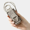 A hand holds an adjustable luggage strap with a quick-release buckle, showing the strap and buckle mechanism.