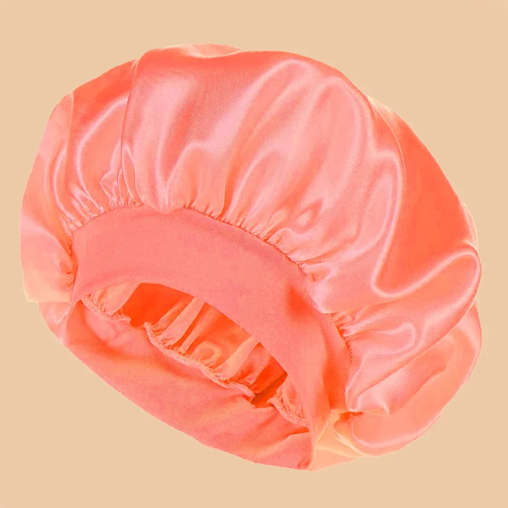 A soft coral pink satin wide brim shower cap for hair protection shown from above.