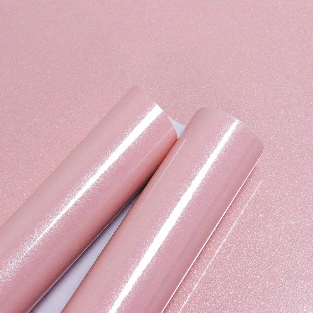 Rolls of glitter pink peel-and-stick vinyl contact paper shown against a pink background.