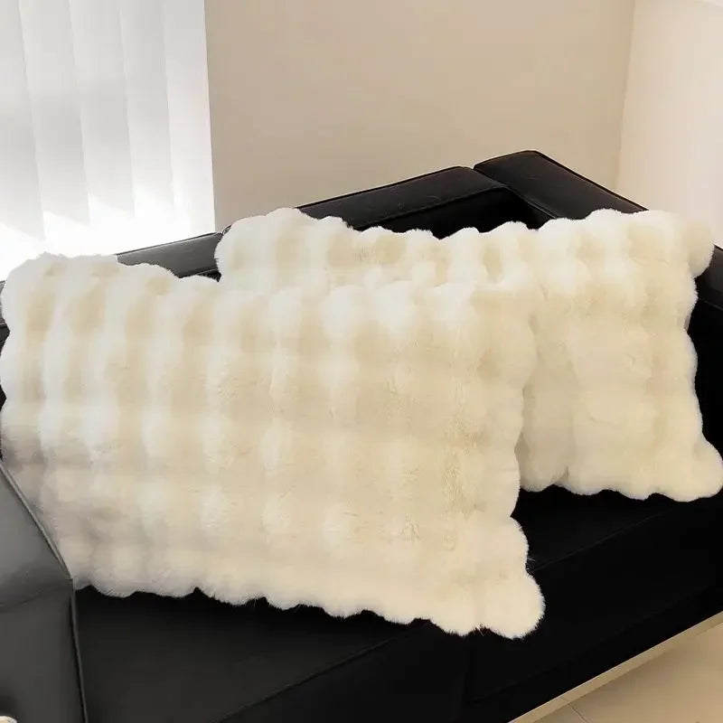 A white, fluffy quilted pillowcase is displayed on a dark surface.