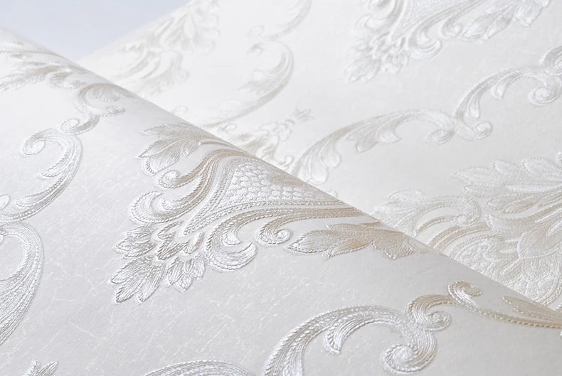 Roll of white embossed damask wallpaper featuring delicate floral scrollwork design.