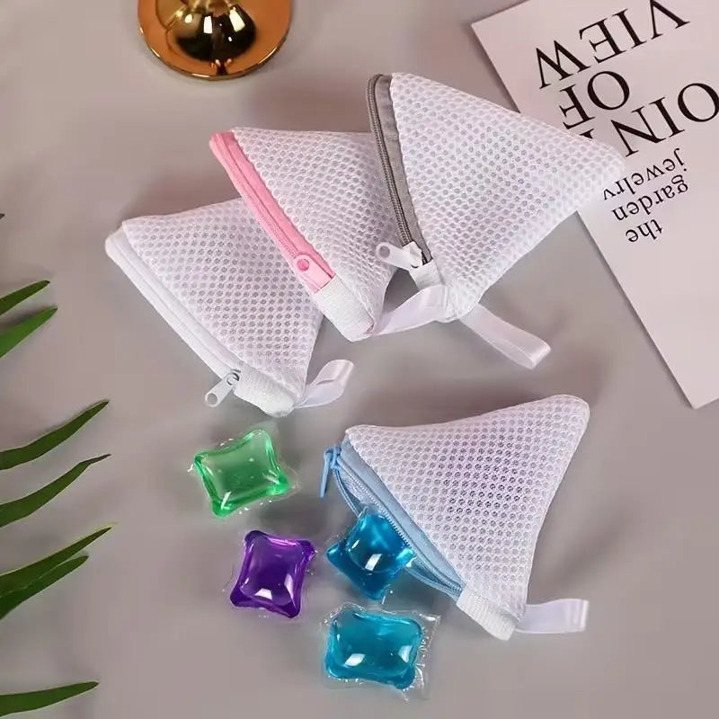 A collection of three reusable white mesh laundry bags filled with colorful liquid soap or detergent.