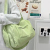 A light green canvas travel tote bag with a strap is shown next to a gray sweatshirt and a framed sign.