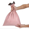 A hand is holding a pink waterproof poly mailer shipping bag with a black ribbon tied at the top.