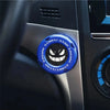 A close-up of a blue rotating protective cover for a car ignition start button featuring an engine graphic.