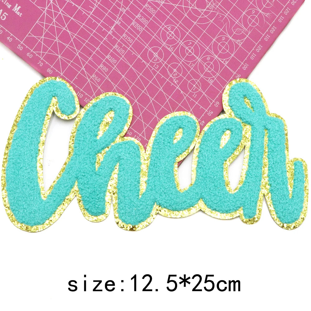 Turquoise glitter chenille letter patch spelling Cheer on pink graph paper