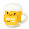 A yellow crocheted mug with a white fluffy handle and a yellow tag that reads Don't worry beer happy