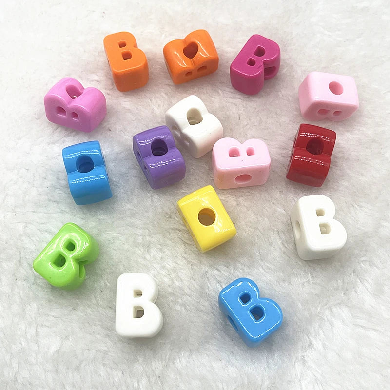 A collection of 10 mixed alphabet letter beads in various colors including orange, purple, pink, and white, scattered on a wh