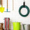 A collection of tools and a heavy duty extension cord organizer with buckle locks displayed on a white brick wall.