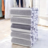 A stack of gray and white striped microfiber bath towels on a light floor.