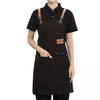 A black cotton canvas apron with adjustable straps and multiple pockets shown on a person.