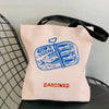 A pink canvas tote bag featuring a blue illustration of sardines and the word Sardines printed in orange.
