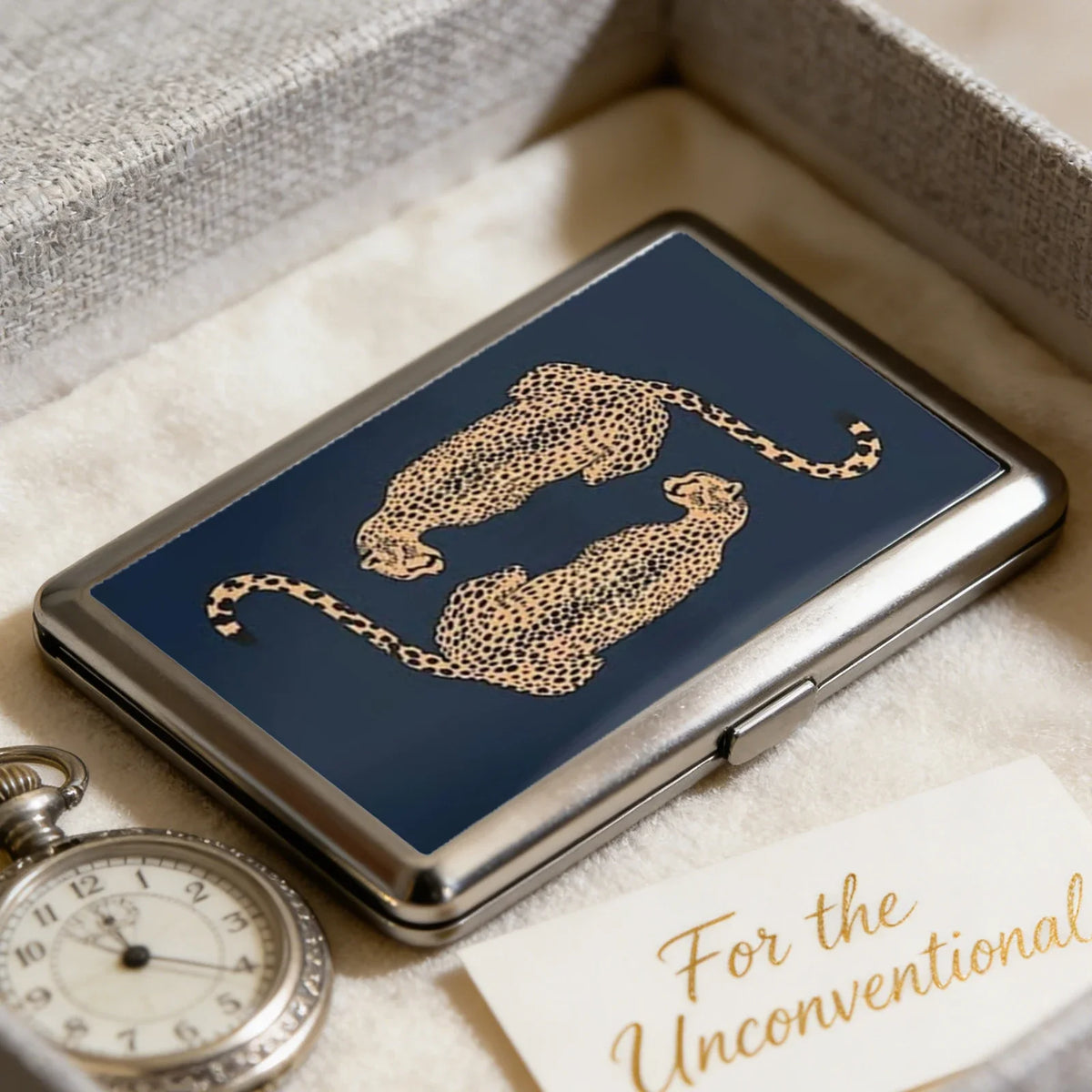 A vintage metal card and cash case with an art deco design featuring a gold leopard print on a dark blue background.