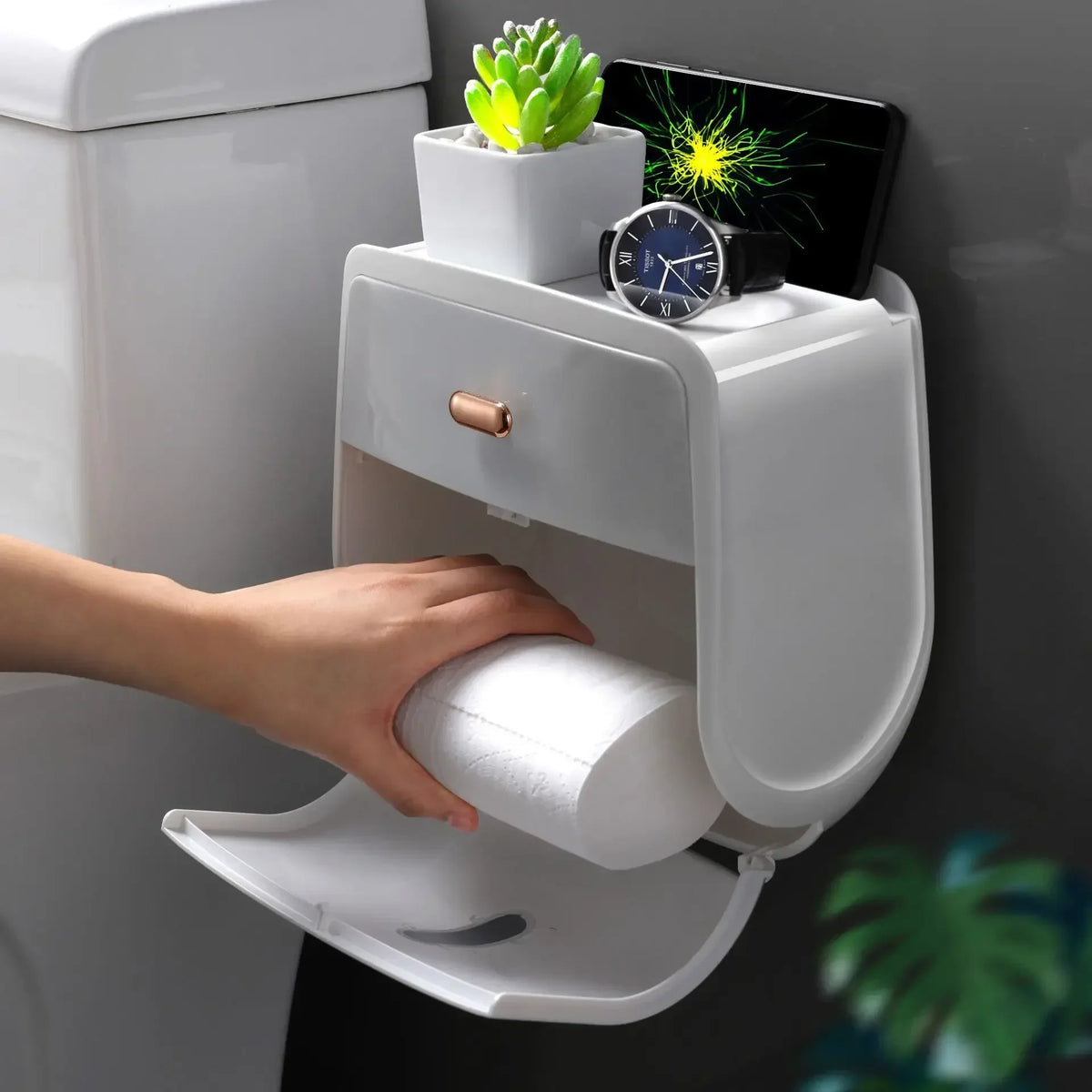 Una mano coloca papel higiénico en un soporte de pared que presenta un reloj y una planta verde.