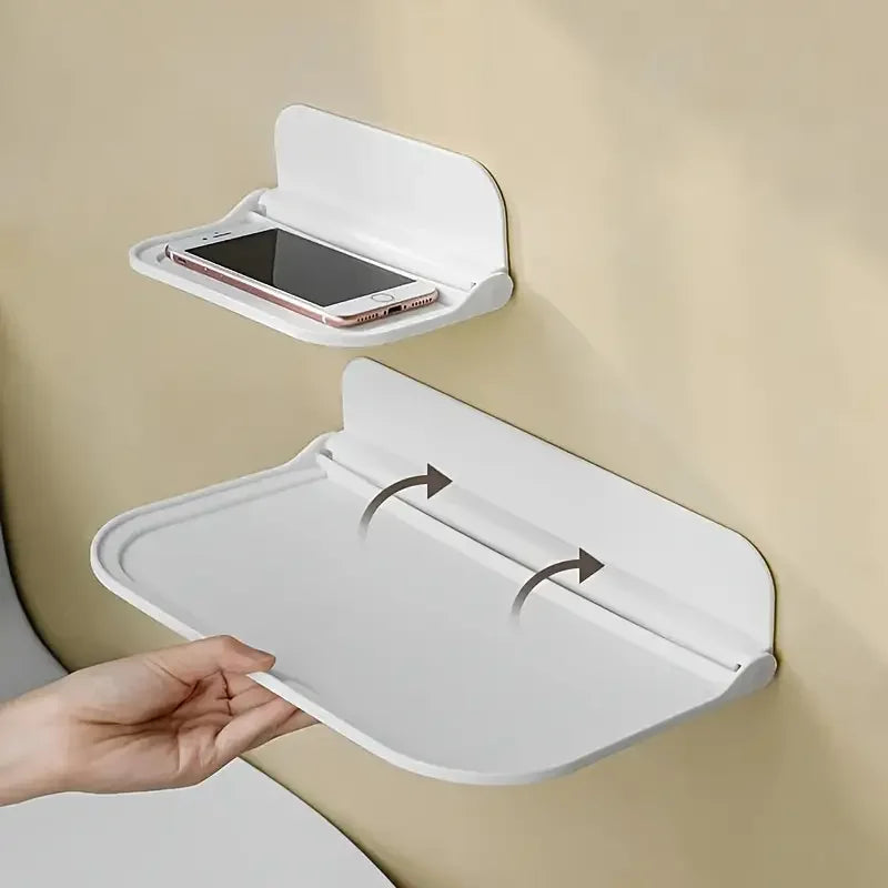 A white foldable no-drill wall shelf is shown with its lid open, displaying a smartphone inside.