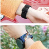 A close-up of a wrist wearing a black quick-release braided nylon watch band next to an orange knitted sleeve.