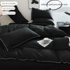 A black duvet cover set with two pillowcases displayed on a bed, next to a framed picture.