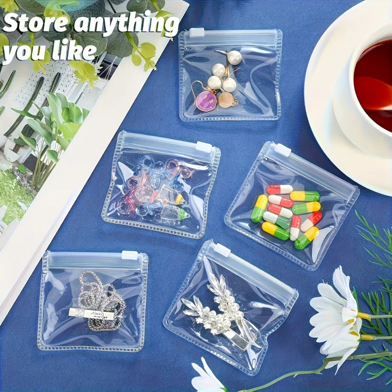 Clear plastic organizer bags filled with various small items like jewelry and pills on a blue surface.