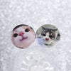 A pair of glossy tinplate pins featuring cute cat faces and expressions.